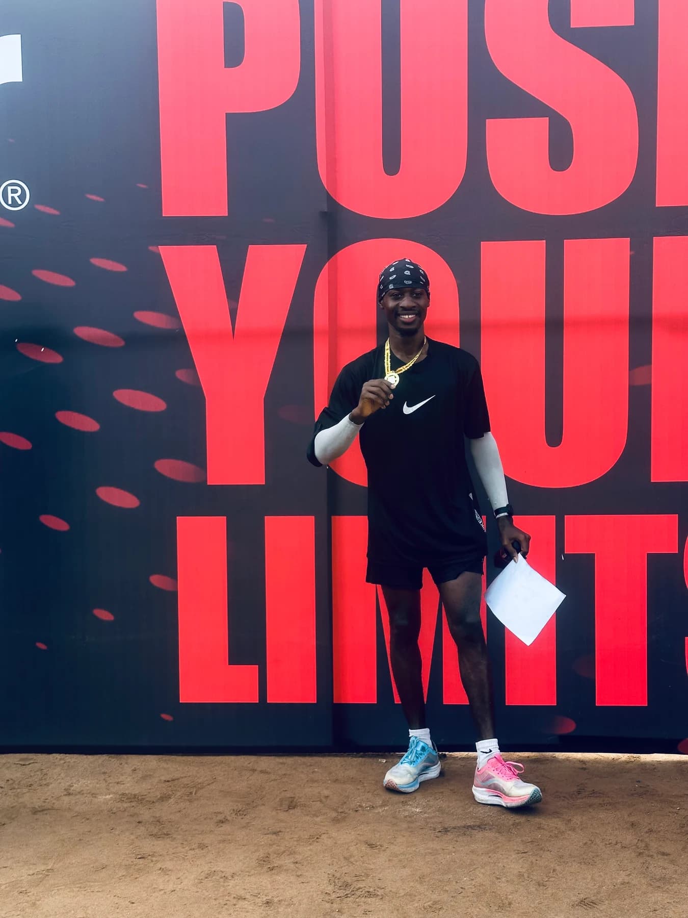 Bolade holding up a race medal in front of a red and dark event backdrop.