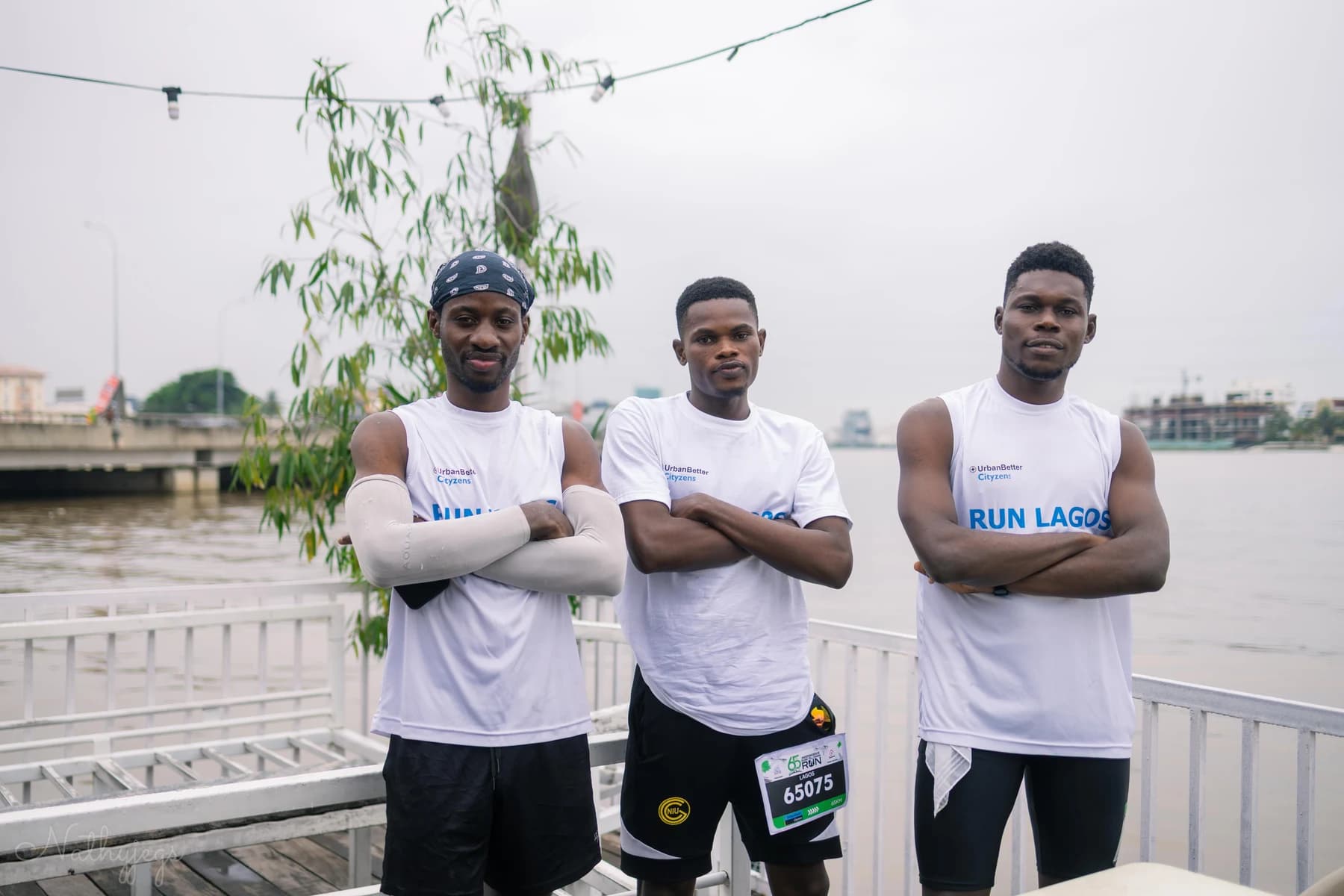 Three runners in Run Lagos shirts standing together by the waterfront.